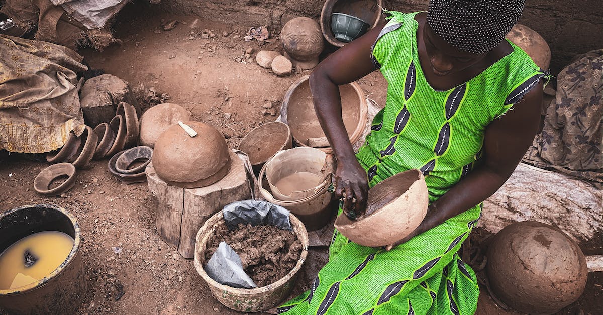 Is it possible to create a Villager who sells pufferfish? - High angle of concentrated African female in light dress sitting on dirty ground of local workshop and creating clay utensils