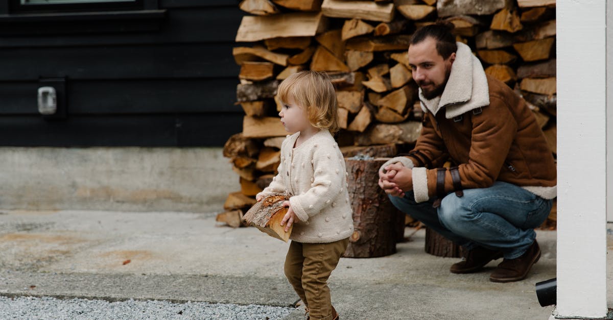 Is it possible to have a strong scout? - Cheerful man smiling while sitting and looking at child while playing with firewood in yard and having fun together during weekend Is it possible to have a strong scout? - Cheerful man smiling while sitting and looking at child while playing with firewood in yard and having fun together during weekend