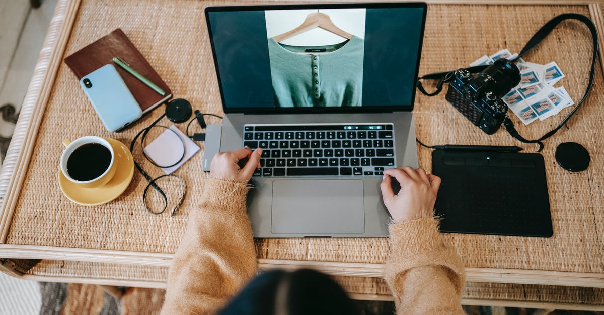 Is it possible to play ultra graphics games online where the actual graphics computing is happening in remote location? - High angle of crop unrecognizable female designer showing photography of apparel on netbook screen at desk with coffee in house
