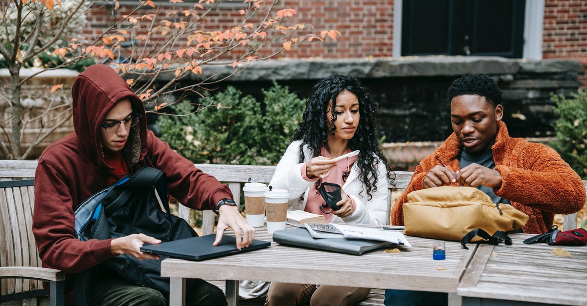Is it possible to put a dweller on coffee break? - Group of multiethnic students sitting at wooden table with takeaway coffee while putting notebook in rucksack during studies on terrace