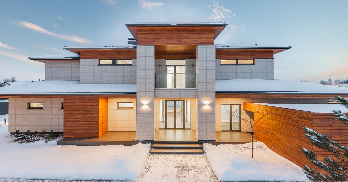 Is it possible to revisit these locations? - Backyard view of new modern luxurious cottage house with stone and wooden facade and illumination in winter countryside