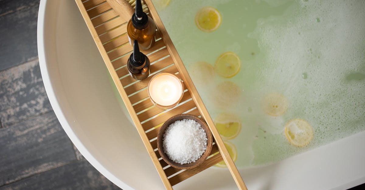 Is it possible to set puddles of water on fire? - Top view of wooden tray with salt and bottles of cosmetic products placed on white tub with lemon slices on water surface