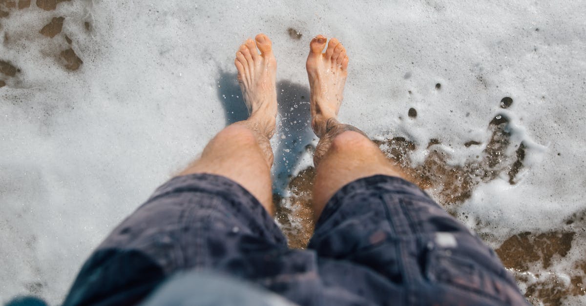 Is it possible to Short Jump on the 3DS? - From above of crop anonymous barefooted male traveler in shorts standing on sandy beach of foamy sea during summer holidays