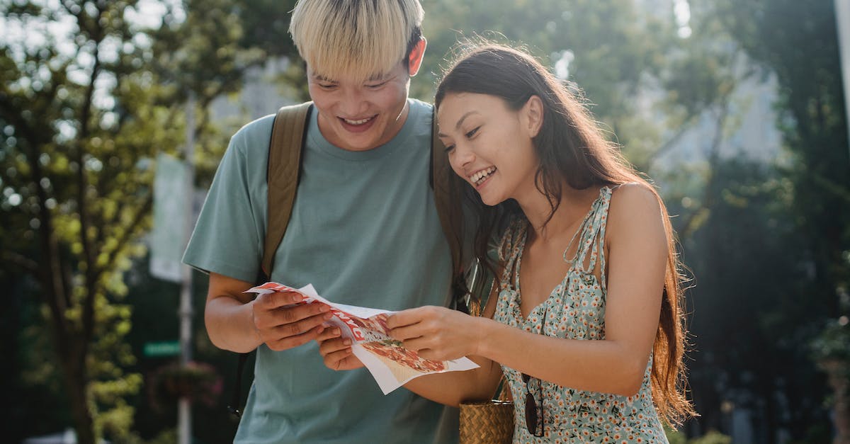 Is it possible to travel into / interact with NPCs in enemy faction territories? - Cheerful multiracial couple of tourists watching map in city