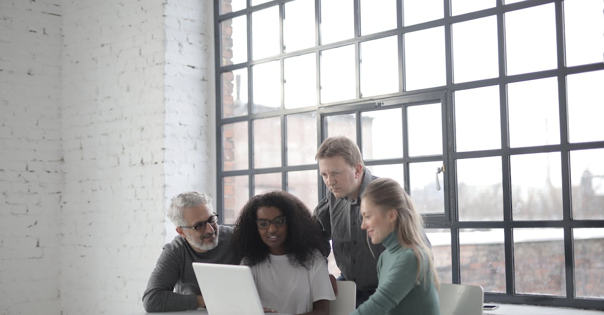 Is it possible to use different teams for different users? - Cheerful diverse colleagues of different ages using laptop in creative workplace