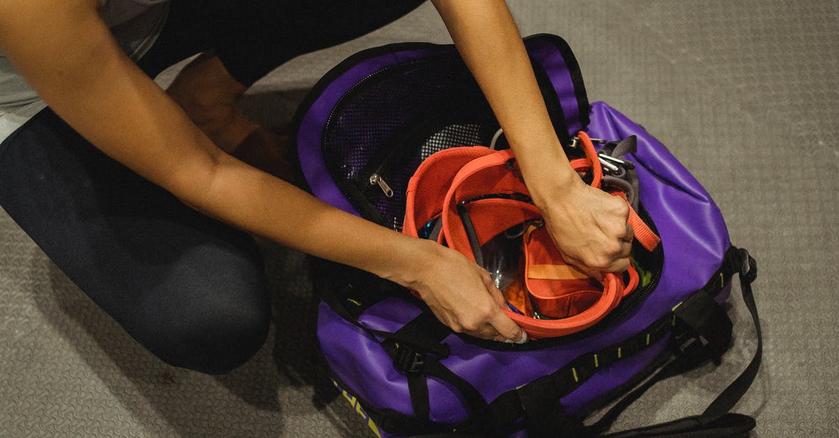 Is it safe to put multiple snitches and ex-cops in a dormitory? - From above of crop anonymous female athlete sitting on floor and packing safety belt in bag after training in contemporary gym