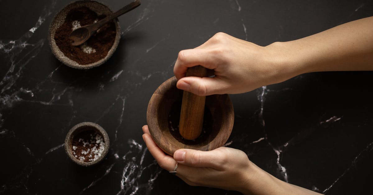 Is it viable to grind above Normal for Torment now? - From above of crop unrecognizable female using pestle while grinding fresh aromatic coffee in mortar on black marble table