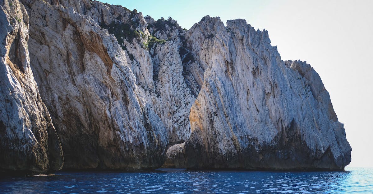 Is the 'Heaven' in Miner's Heaven meant literally? - Range of tall steep beige mountains with bushes on top on shore of ocean under light blue cloudless sky