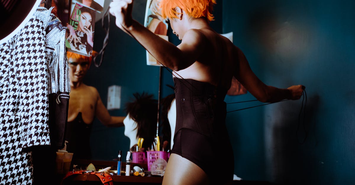Is the character deck common or individual? - Sensual young ethnic transsexual guy tying corset in dressing room