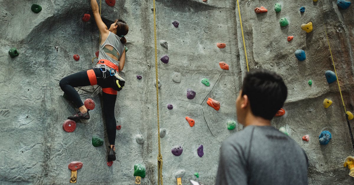 Is the result of your training session random, or related to something the user controls? - Back view of young female climbing wall while man writing results and watching