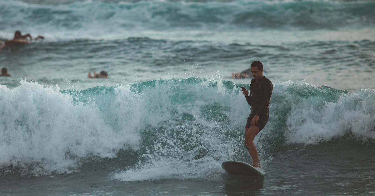 Is the Wii Fit U board compatible with the original Wii? - Young male surfer in short wetsuit riding surfboard and using mobile in magnificent restless sea with other surfers paddling behind Is the Wii Fit U board compatible with the original Wii? - Young male surfer in short wetsuit riding surfboard and using mobile in magnificent restless sea with other surfers paddling behind