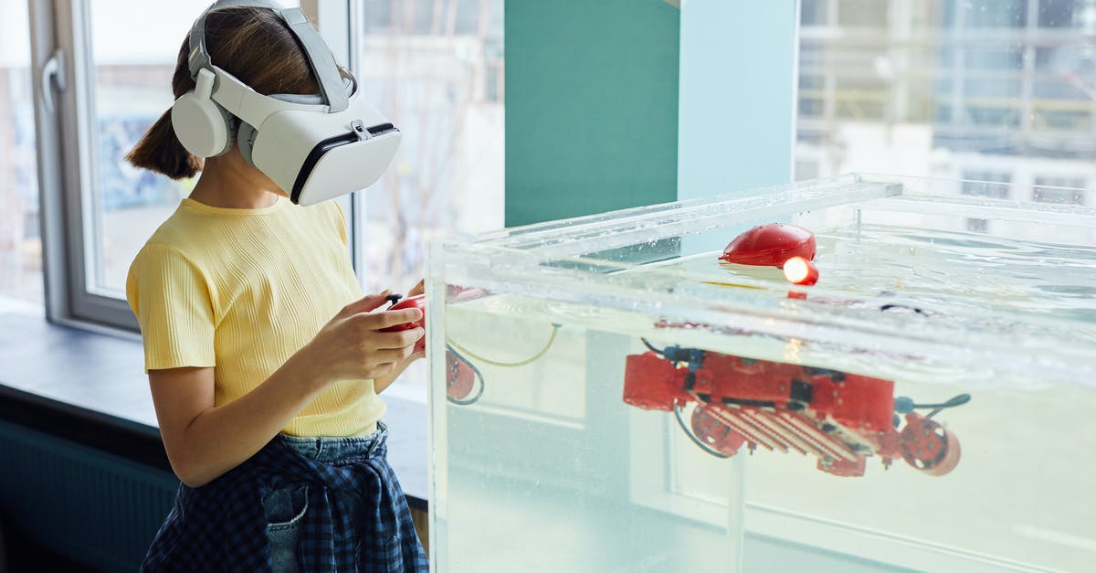 Is there a limit of robots the game can handle? - Side view of little girl wearing VR goggles and exploring new robot with controllers in light room