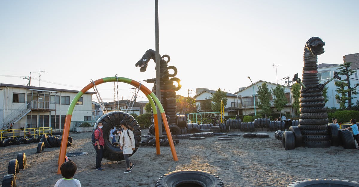 Is there a mass use for rubber or sticky resin? - Small yard with huge monster creature figures constructed of old tyres on playground full of children