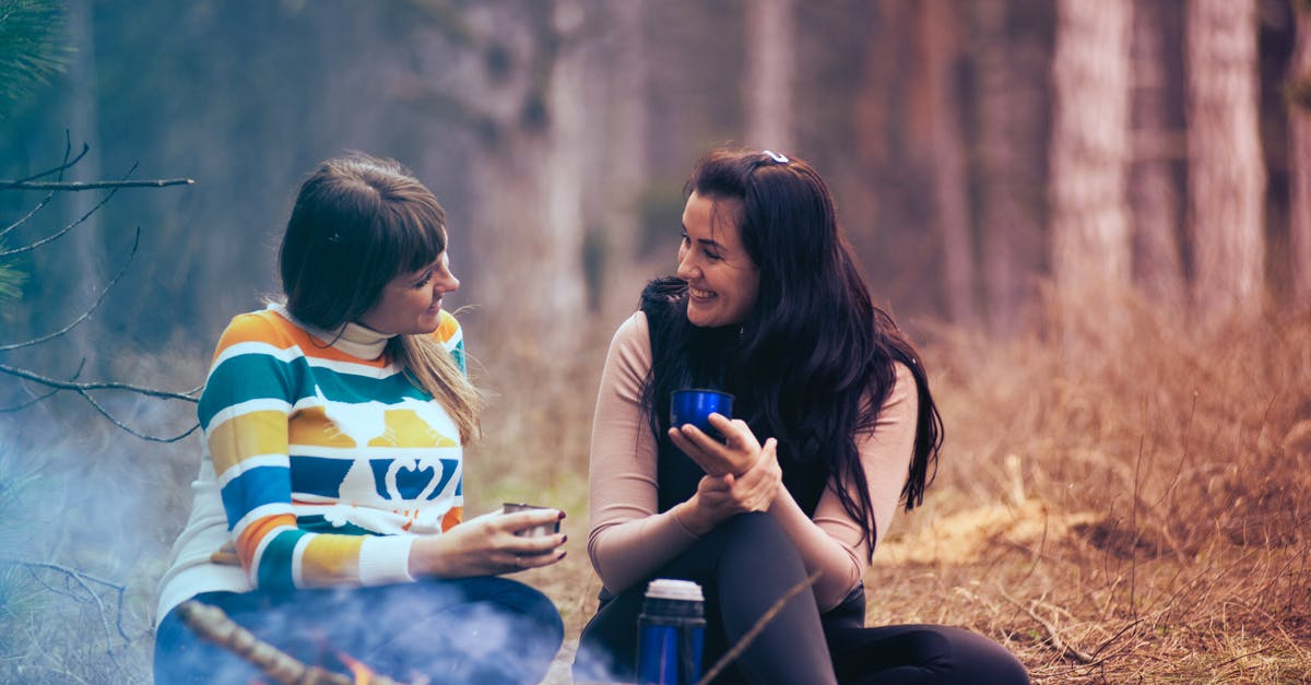 Is there a point listening to people talking among themselves? - Two Women Sitting on Ground Near Bonfire