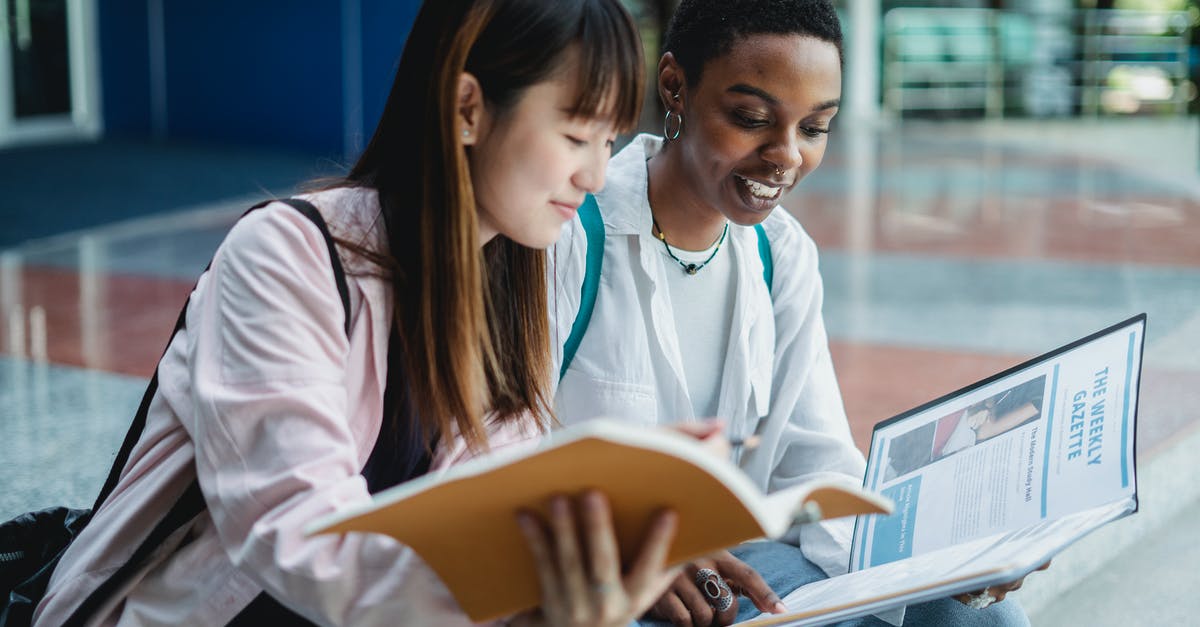 Is there a point to interacting with Pokemon in your lobby/city area? - Smiling diverse students sharing book while studying on urban staircase
