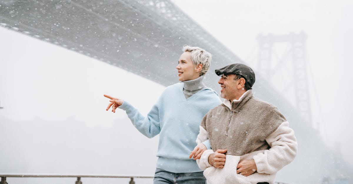 Is there a point to interacting with Pokemon in your lobby/city area? - Adult female showing river to male partner while talking against urban bridge in fog and looking away