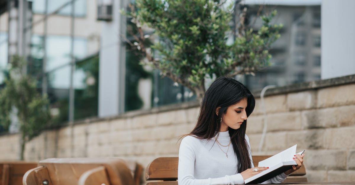 Is there a story I should be paying attention to in Dark Souls? - Serious ethnic female in stylish outfit reading textbook while spending time at table in park Is there a story I should be paying attention to in Dark Souls? - Serious ethnic female in stylish outfit reading textbook while spending time at table in park