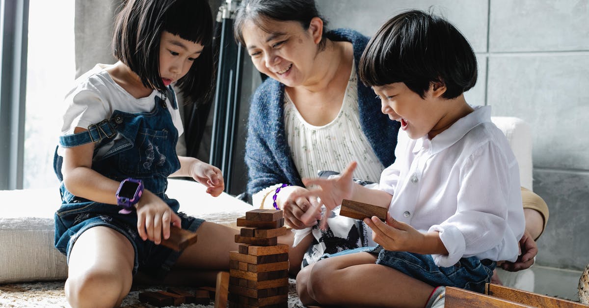 Is there a way to clone relative coordinates of a player and the command block? [duplicate] - Happy grandmother sitting on floor with Asian boy and girl while playing with wooden blocks and building tower in living room near window