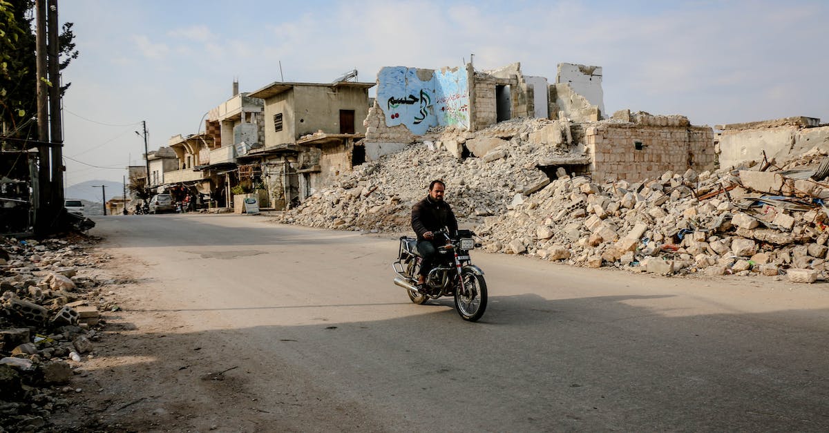 Is there a way to destroy spike balls? [duplicate] - Active man riding motorcycle on empty straight roadway along destroyed buildings and piles of ruined houses in district of town
