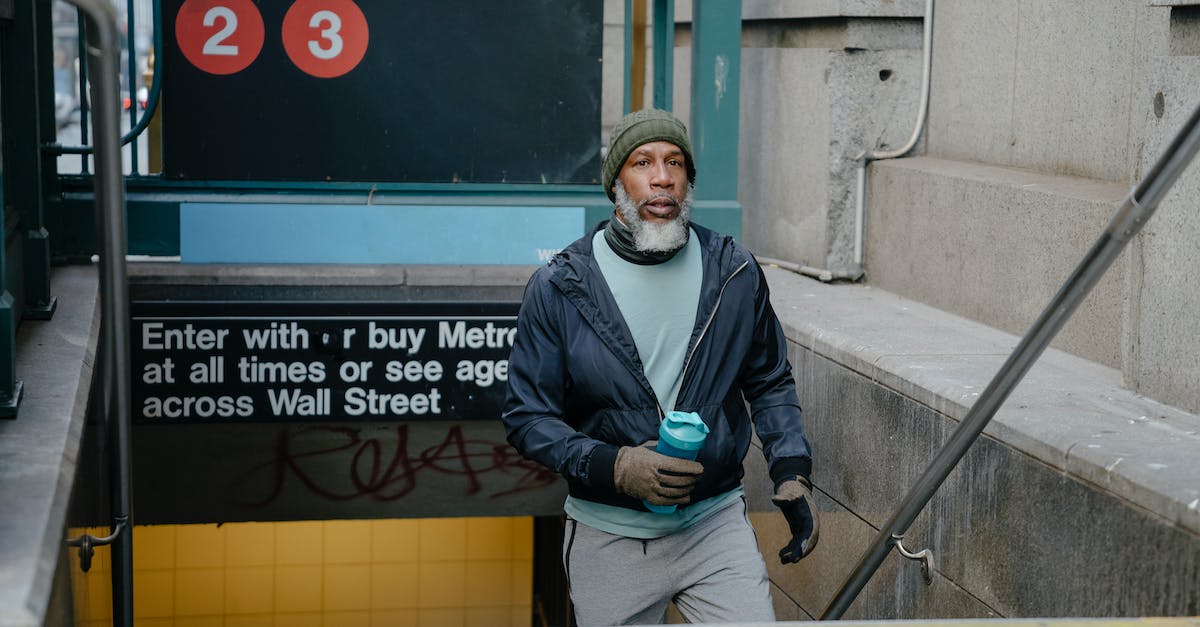 Is there a way to exit demo mode on the PS4 kiosk? - Thoughtful senior African American male in warm jacket and knitted hat and gloves and fitness bottle in hand going upstairs from underground passage of subway station