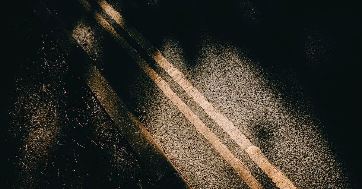 Is there a way to get rid of dirt patches? - From above of asphalt roadway with yellow marking lines with dark shades near ground in sunny day in street