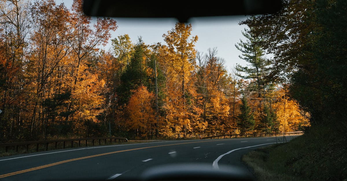 Is there a way to make a kill shooting through a tank window? - Modern car driving along curvy asphalt road amidst lush autumn trees in countryside on sunny day