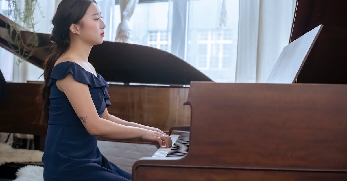 Is there a way to make the keyboard player 2? - Side view of skilled Asian female in elegant outfit performing melody piano while sitting in light room with musical instruments