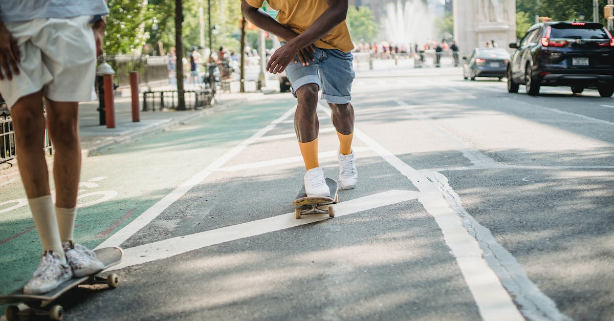 Is there a way to respec my skills? - Crop anonymous multiracial male skaters in casual clothes riding skateboards along asphalt road in sunny day