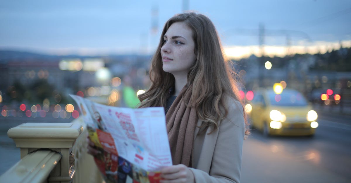 Is there a way to see collectibles on the map? - Female traveler in warm clothes standing on street with map and looking away at dusk