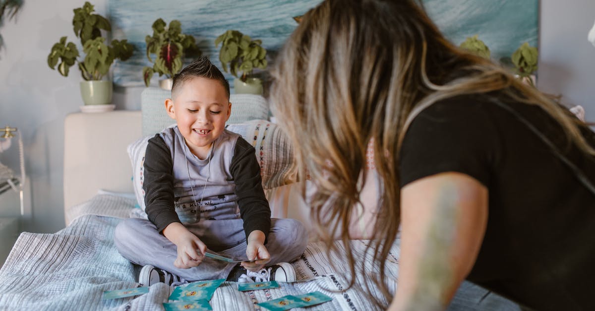 Is there a way to show in game time? - Cheerful kid playing cards game with unrecognizable mom on bed