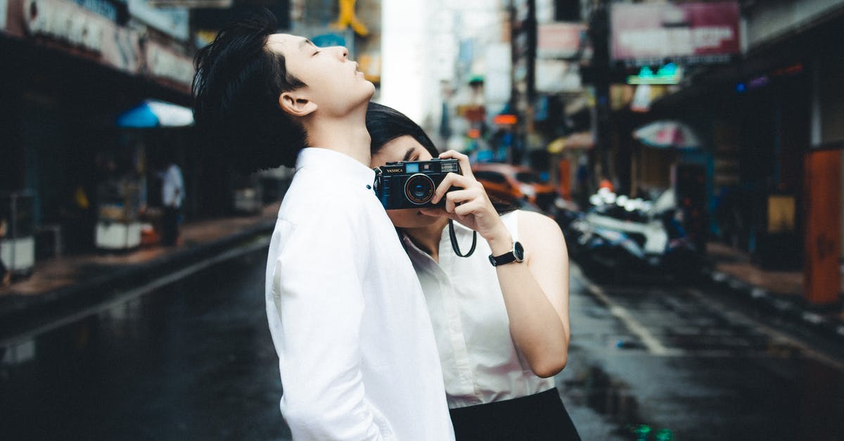 Is there a way to take picture outside would encounters? - Elegant Asian couple with photo camera on road Is there a way to take picture outside would encounters? - Elegant Asian couple with photo camera on road