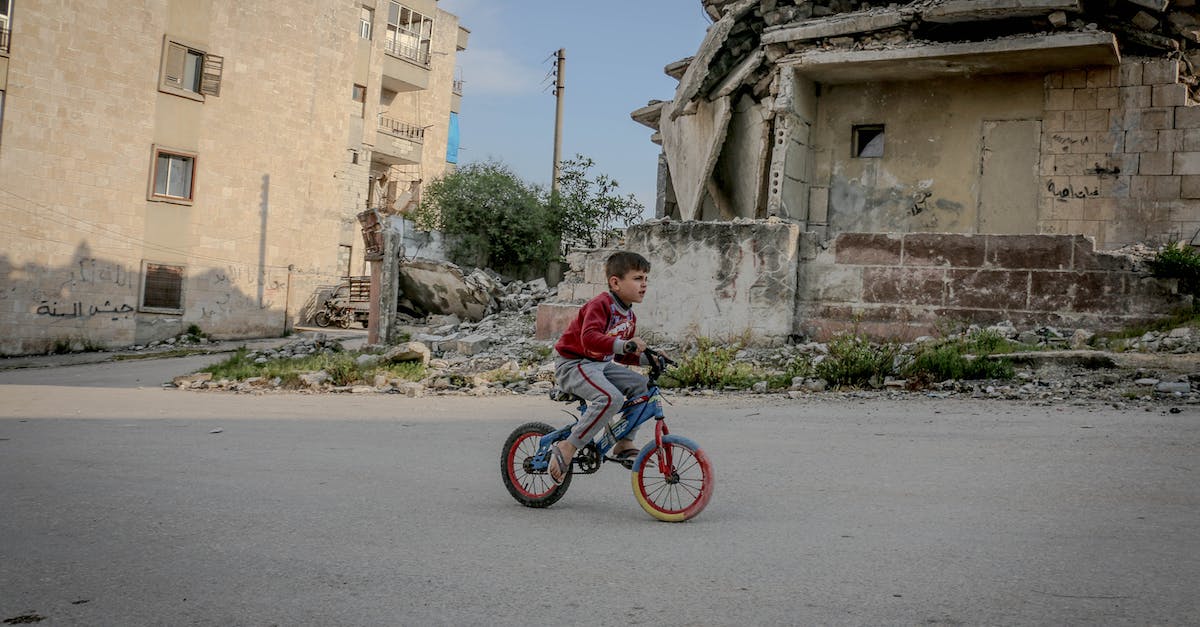 Is there a way to tell how many buildings have been destroyed in SC2 - The Dig? - Full body side view of boy in casual clothing riding on bicycle along old ruined construction in daytime