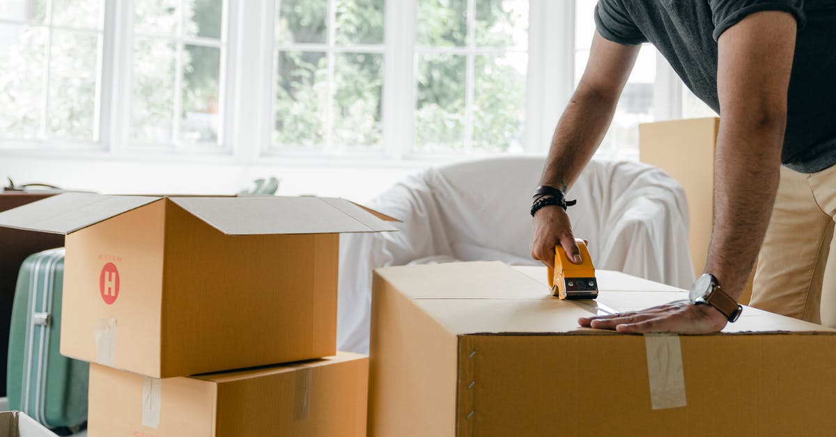 Is there a way to tell when the dispensers are going to dispense their item? - Crop unrecognizable man in casual clothes packing carton box using scotch tape dispenser for moving personal items to new apartment