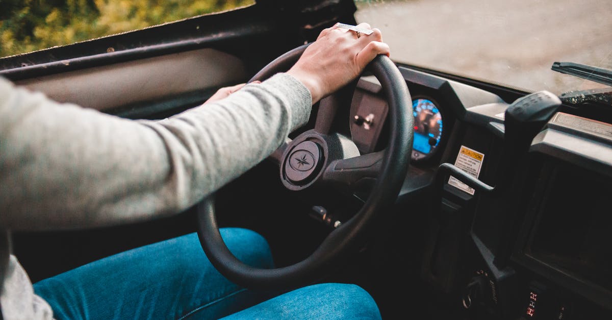 Is there an easy way to route power to the inside of buildings? - Faceless driver in grey sweater and jeans using big black round spinning wheel while driving automobile in countryside