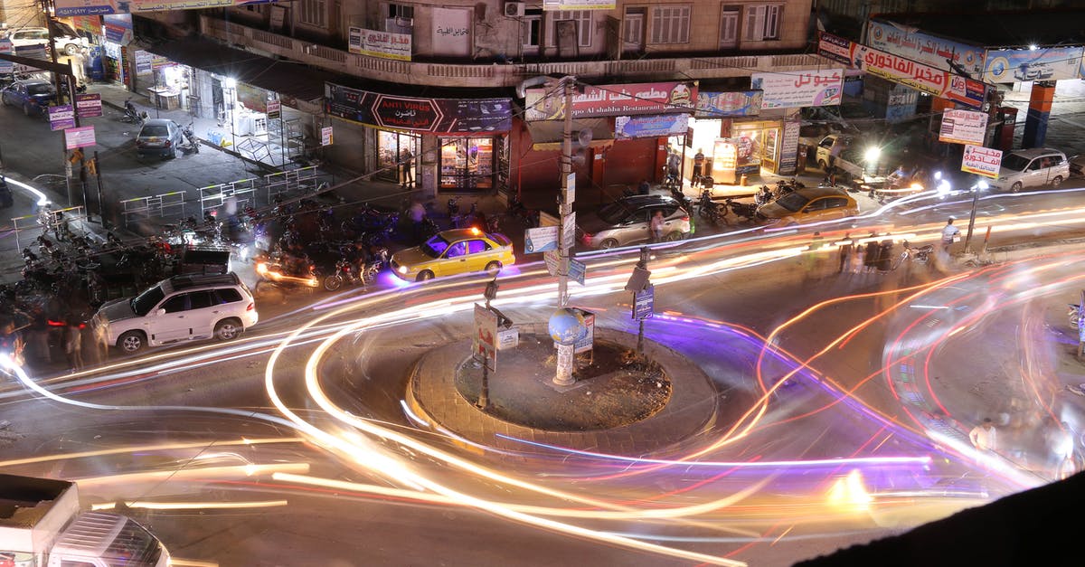 Is there an easy way to route power to the inside of buildings? - From above long exposure of cars riding on road surrounded by parked automobiles and tall multi storey constructions at night