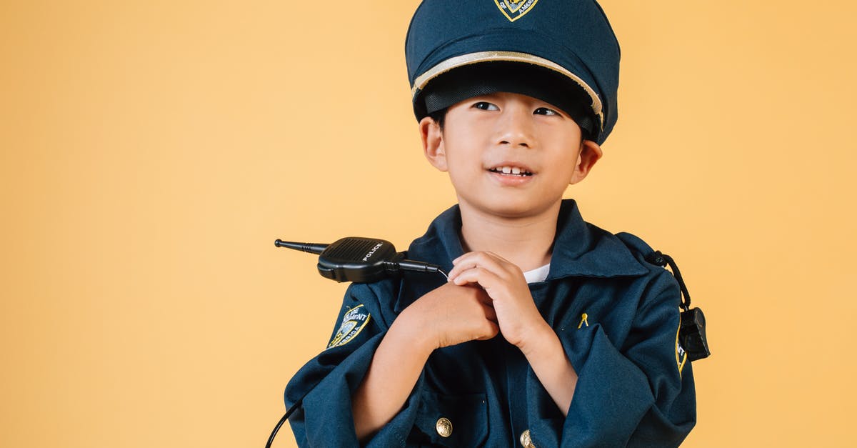 Is there an order to playing Skyrim and the DLCs? - Pleasant Asian boy in police uniform and cap looking away while standing with hands near chest in studio on yellow background