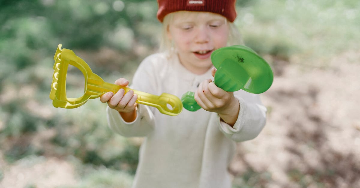 Is there any advantage to lingering in sandbox mode? - Adorable child playing with toys shovel and rake in park