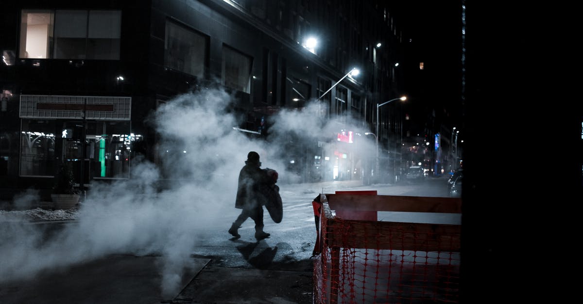 Is there any way I can do key combos on a steam controller (mac) - Side view of distant anonymous person crossing asphalt roadway on street with steam and residential buildings at night time in city