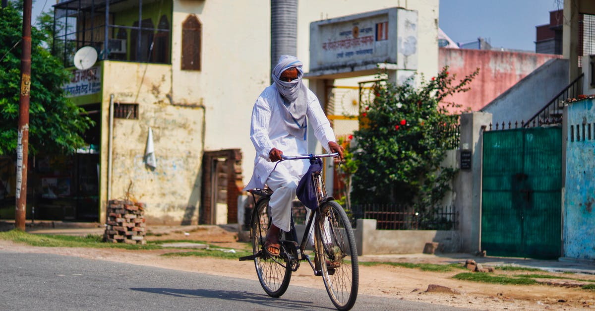 Is there any way I can dress as Bruce Wayne? - Full body faceless Asian male wearing white long dress and headscarf riding bicycle through asphalt road on rural street Is there any way I can dress as Bruce Wayne? - Full body faceless Asian male wearing white long dress and headscarf riding bicycle through asphalt road on rural street