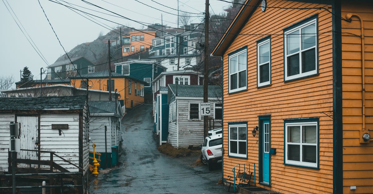 Is there any way to get power armor to a settlement without wearing it? - Pathway between shabby residential buildings located in town with power lines near rocky slope against cloudy sky in foggy weather