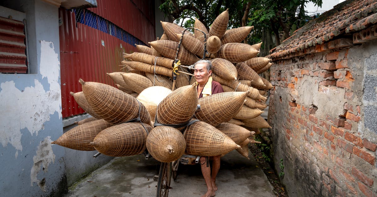 Is there any way to have a villager trade materials for armor? - Elderly Asian man carrying bamboo fish traps on street in poor district of village in daylight