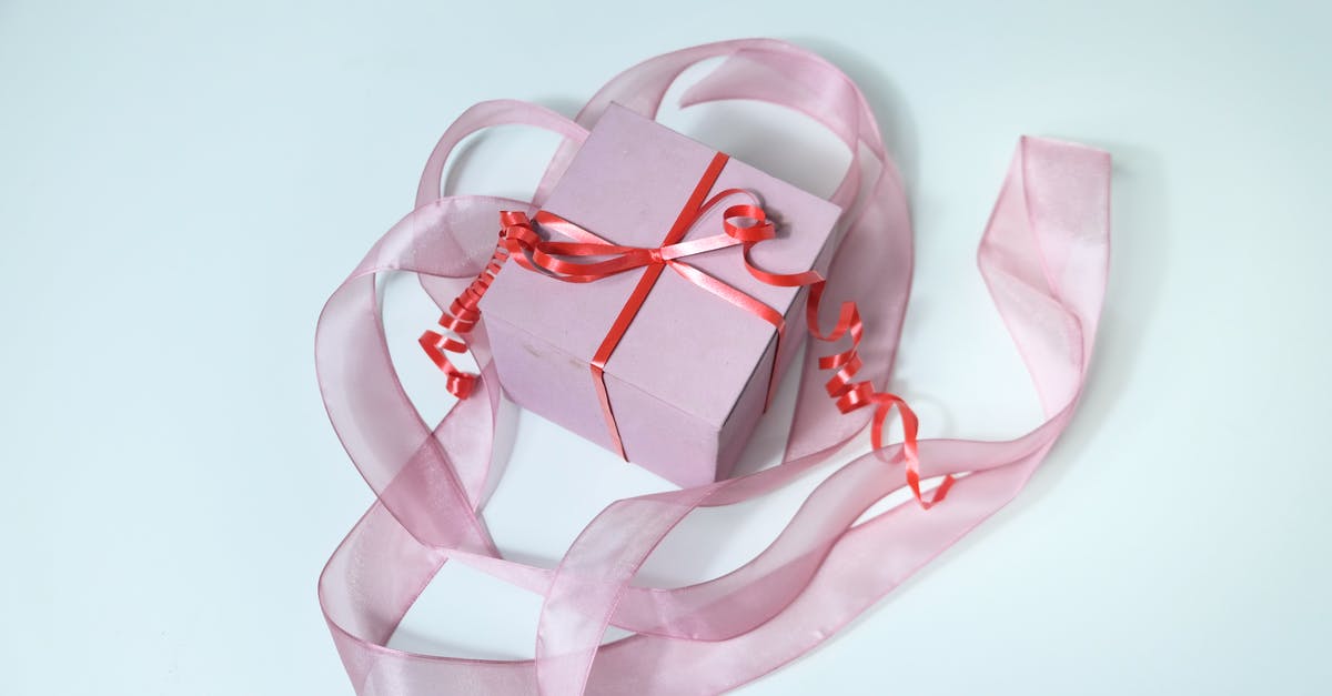 Is there anything special about Christmas Day? - From above of pink cardboard gift box tied with red band and decorated with ribbon on gray background