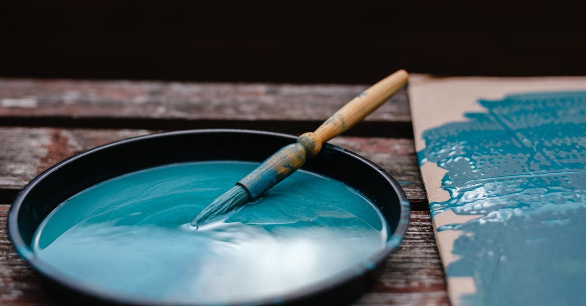 Is there anyway to refill a repair tool outside of a garage? - Dirty paintbrush dipped in bowl with azure paint near colorful turquoise carton on wooden bench in street with black background