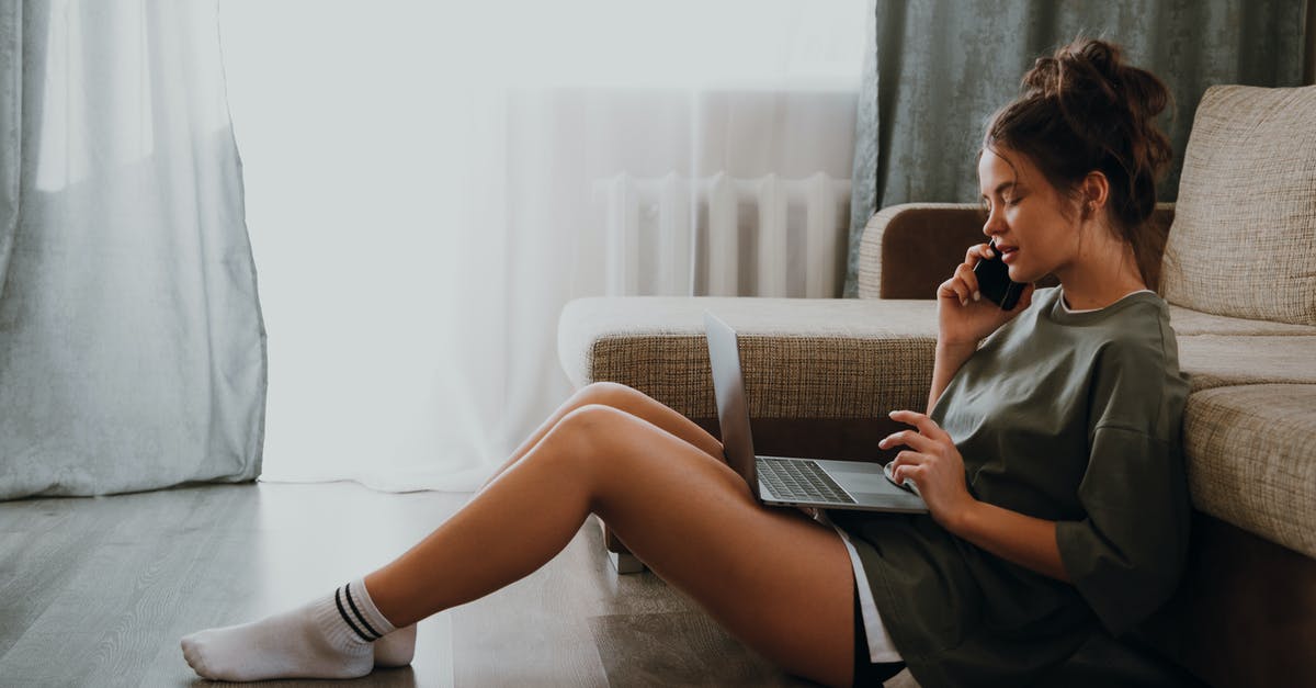 Is there mass phone call in Watch Dogs series? - Side view of young female in domestic outfit sitting on floor near sofa and browsing netbook while talking on mobile phone at home