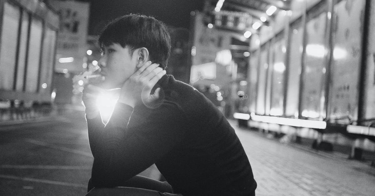 Is upgrading my town hall without upgrading defenses a bad idea? - Black and white young ethnic man sitting on pavement and smoking cigarette in evening in city