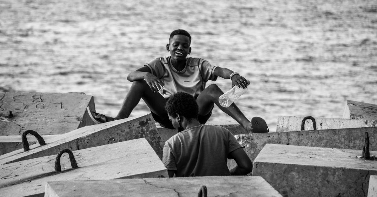 (Java Minecraft 1.13) How to summon a splash water bottle with no gravity? - Black and white of African American friends resting among breakwater rocks near sea