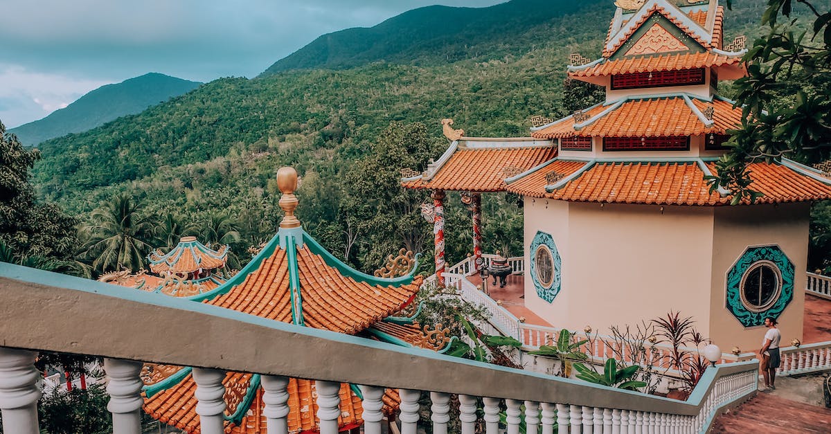 Jungle Temple percentage - High angle of traditional oriental shrine located in calm green park with tropical palms and tourist at distance