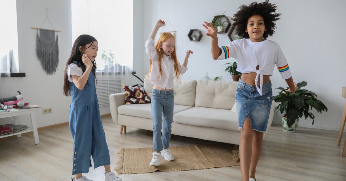 Just Dance 2021: How much content is offered in "Kids Mode"? - Content multiracial children dancing with raised arms on floor near sofa in living room Just Dance 2021: How much content is offered in "Kids Mode"? - Content multiracial children dancing with raised arms on floor near sofa in living room