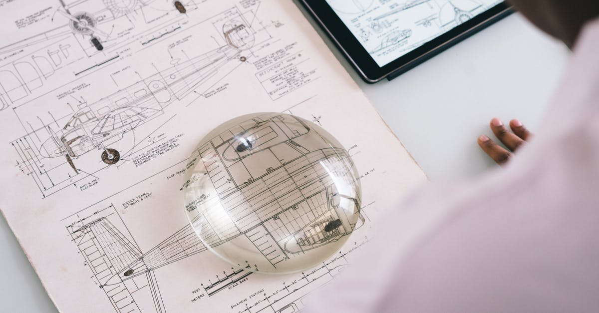 Keep user data when migrating map from Realms to the server - Crop unrecognizable mechanic holding magnifying glass on paper with airplane drawing while working on project on tablet in aircraft factory