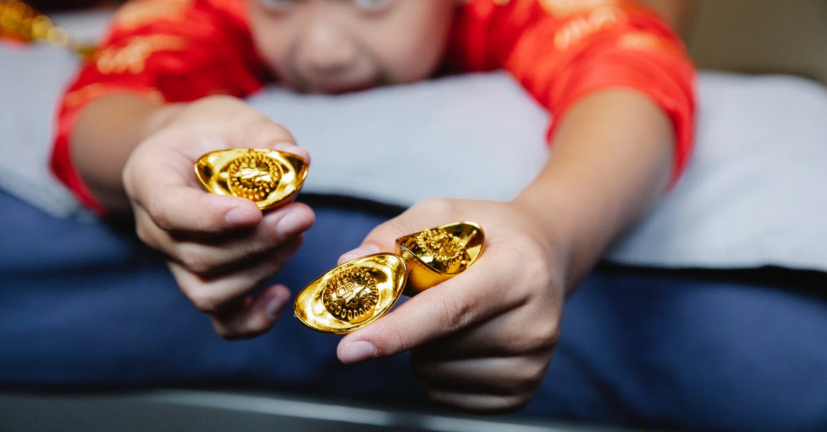 Kids cannot access gold content with Xbox Live Gold Sharing - Crop happy little Asian boy lying on bed and demonstrating traditional sycee gold ingots during celebration of Chinese New Year